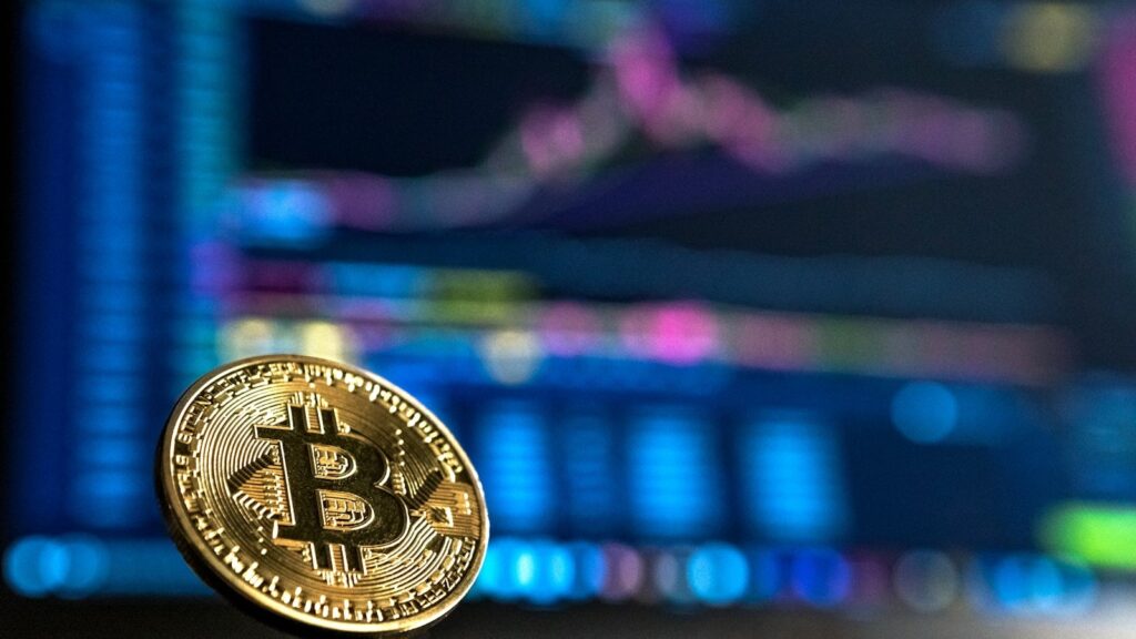 Pièce Bitcoin devant un graphique de cours